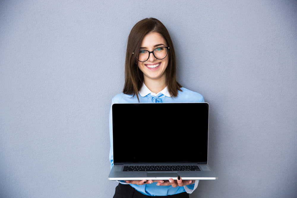 businesswoman or employee smiling and holding a laptop 