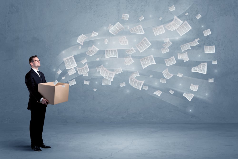 Office documents, contracts, papers flying out of cardboard box being held by a young business worker concept.