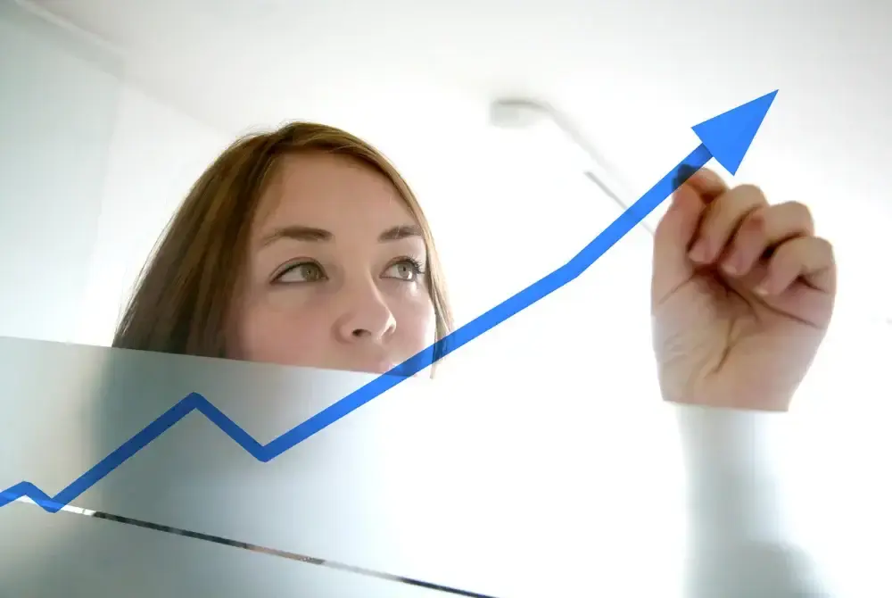 woman drawing an up arrow on a dry erase board